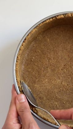 a person holding a spoon in a pie pan with the crust on it's side