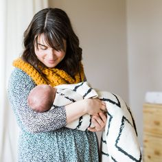 a woman holding a baby wrapped in a blanket