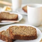 two slices of banana bread sitting on top of a white plate next to a cup of coffee