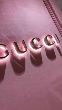 the word gucci is lit up against a pink wall