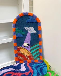 colorful rugs are stacked on top of each other in front of a book shelf