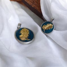 two pieces of jewelry sitting on top of a white cloth