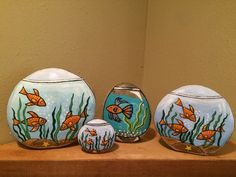 three vases with fish painted on them are sitting on a shelf in front of a wall