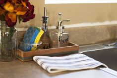 a kitchen sink with towels, soap dispenser and flowers on the counter