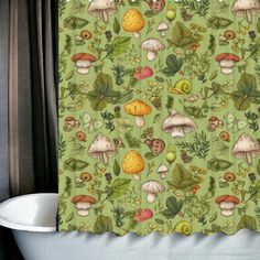 a green shower curtain with mushrooms and leaves on it in front of a bathtub