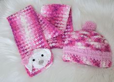 a pink hat, scarf and mittens are laying on a white fur surface