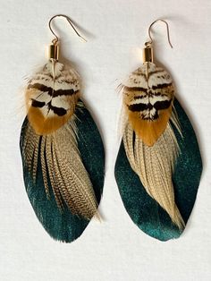 two pairs of earrings with feathers hanging from them