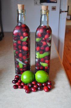 two bottles filled with cranberries and limes next to each other on a counter