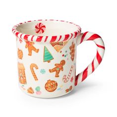 a white mug with candy canes and gingerbread cookies on the inside is sitting in front of a white background