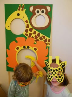 two young children with masks on their faces in front of a wall decoration featuring giraffes and monkeys