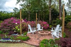 an outdoor fire pit surrounded by flowers and chairs