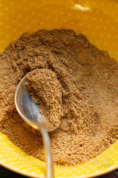 a yellow bowl filled with brown powder and a spoon