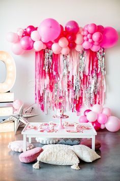 a table topped with lots of pink balloons and tassels on top of it