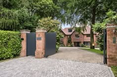 a large brick driveway with an iron gate in front of it and trees on either side