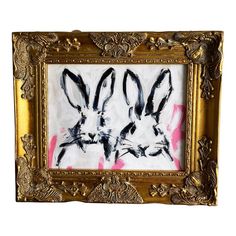 two black and white rabbits are in a gold frame with pink paint splattered on it