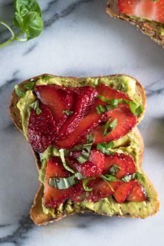 an avocado toast with strawberries and spinach is on a marble surface