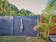 an outdoor shower in the middle of a yard with palm trees and other greenery