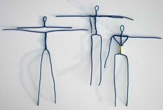 three wire sculptures are hanging on the wall