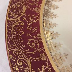 a red and gold plate sitting on top of a white tablecloth covered table cloth