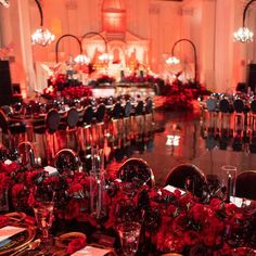 the tables are set with red flowers and place settings