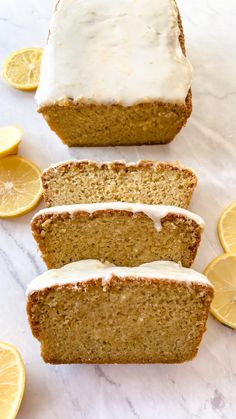 slices of lemon loaf cake with icing and sliced lemons around them on a marble surface