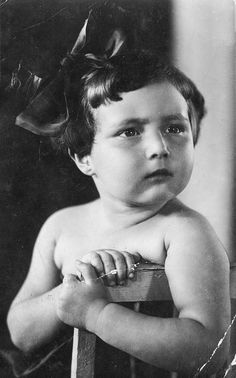 an old black and white photo of a young boy with a bow on his head