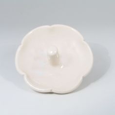 a white porcelain bowl with a flower decoration on the bottom and a single button in the middle