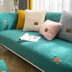 a couch with several pillows on it and a magazine laying on the floor next to it