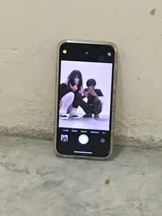 a cell phone is hanging on the wall with two people playing video games in front of it