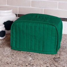 a green storage bag sitting on top of a counter next to two white vases