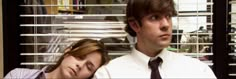 a man and woman sitting next to each other in front of a window with blinds