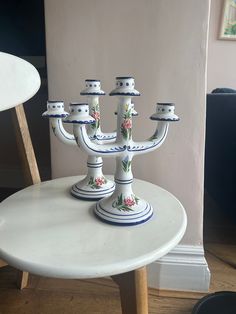 two white candlesticks sitting on top of a table with flowers painted on them