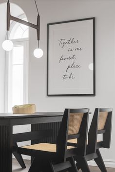 a dining room table with two chairs and a poster hanging on the wall above it