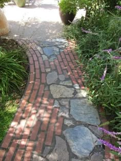 a brick path is surrounded by plants and flowers