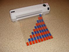 a machine that is sitting on the floor next to an orange and blue piece of paper