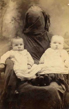 an old photo of two babies sitting on top of each other in front of a woman