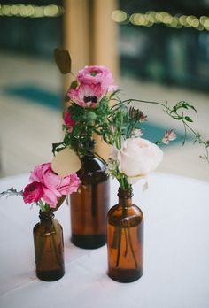 three brown vases with pink and white flowers in them on top of a table