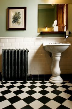 a bathroom with black and white checkered flooring next to a radiator