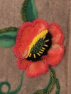 a close up of a flower on a piece of cloth with green leaves and beads