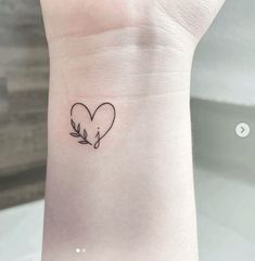 a small heart tattoo on the wrist