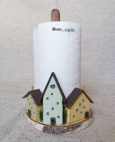 a toilet paper holder with two houses on it and a wooden stick sticking out of the top