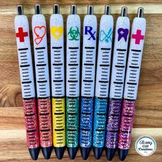 six pens with different designs on them sitting in front of a wooden table and the words love