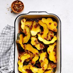 a casserole dish with squash and pecans in it on a white table