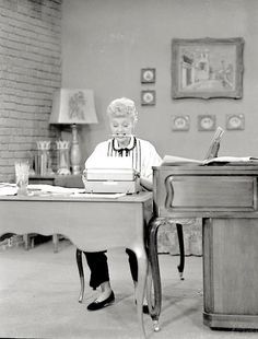 an old woman sitting at a desk in front of a book