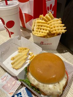 a cheeseburger with waffle fries on the side and a drink sitting next to it