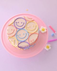 a smiley face cake sitting on top of a pink plate