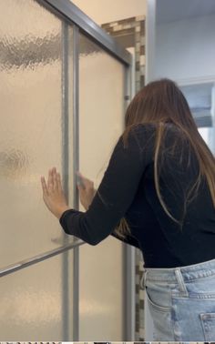 a woman standing in front of a frosted glass door with her hands on it