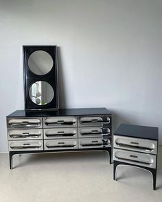 two black and silver dressers sitting next to each other in front of a mirror