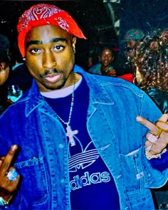 a man in a denim jacket and red hat making the peace sign with his hands