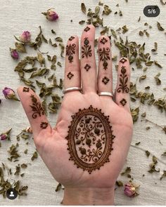 a person's hand with henna tattoos on it and flowers scattered around them